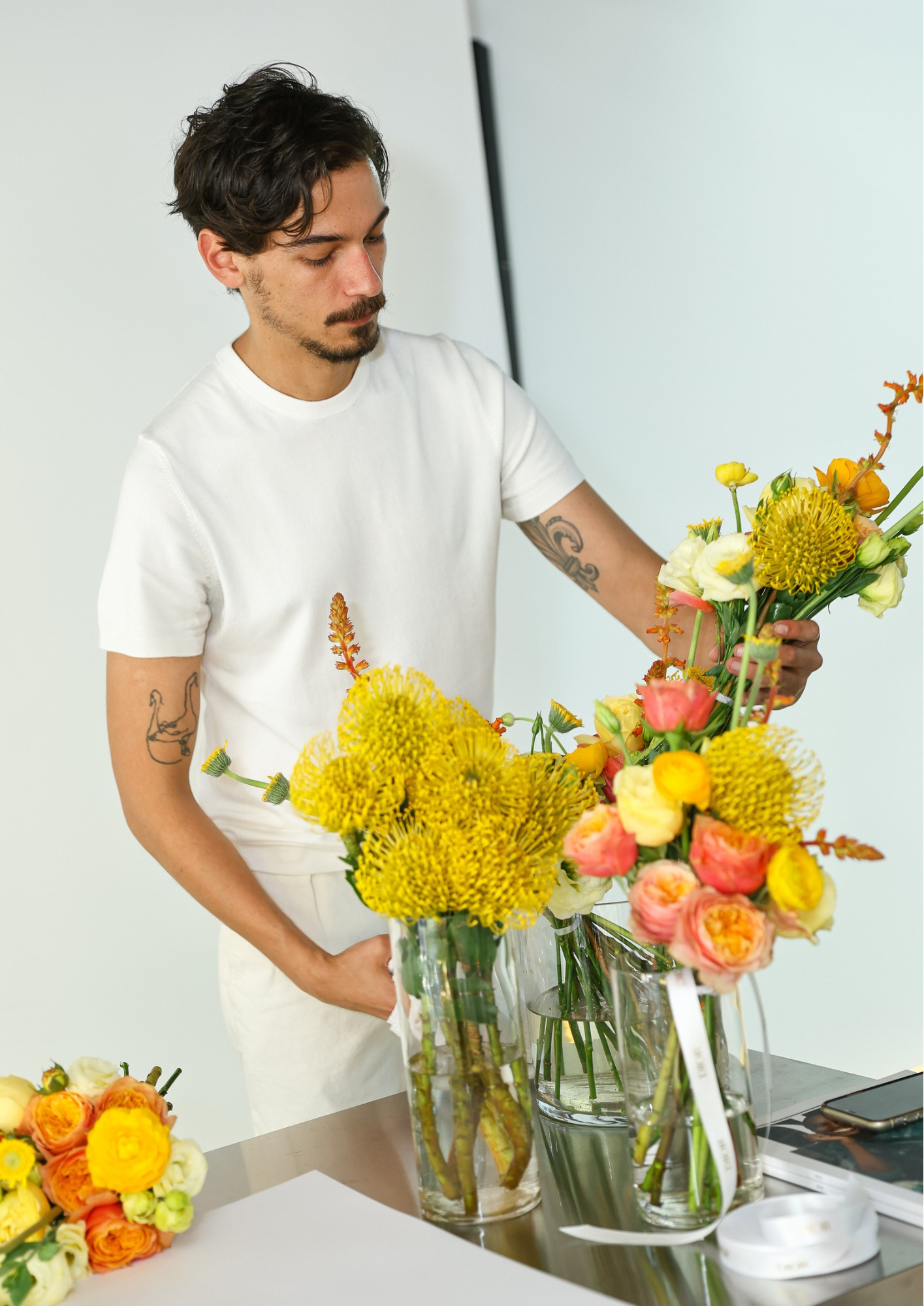 Conrado Pedroso trabalhando em uma composição de flores amarelas, brancas e rosas.